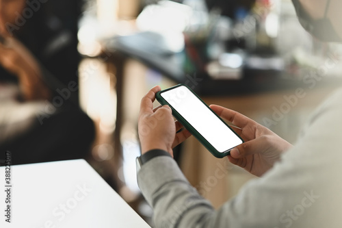 Cropped shot of businessman using smartphone with white screen on white office desk. Blank screen mobile phone for graphic display montage.