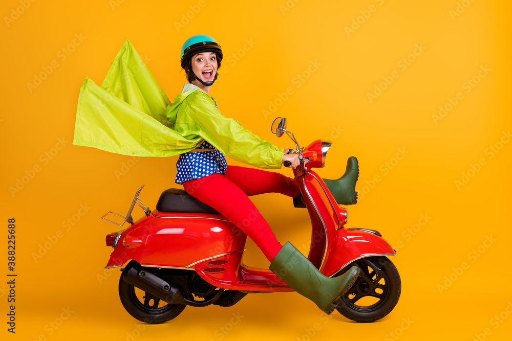 Full length photo portrait of cheerful woman spreading legs riding motorbike isolated on vivid yellow colored background Full length photo portrait of cheerful woman spreading legs riding motorbike isolated on vivid yellow colored background