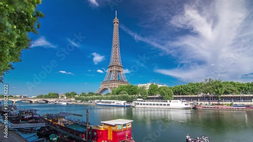 The Eiffel tower timelapse hyperlapse from waterfront at the river Seine in Paris. Ship and boats on river at sunny summer day photo