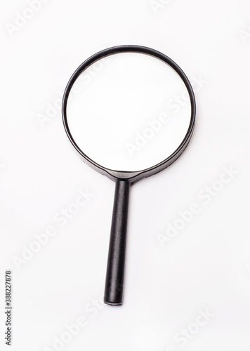 There is a magnifying glass on a light background. Copy space