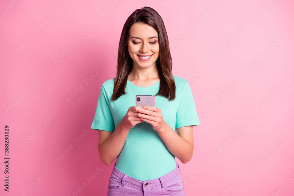 Photo portrait of woman holding phone in two hands texting isolated on pastel pink colored background Photo portrait of woman holding phone in two hands texting isolated on pastel pink colored background