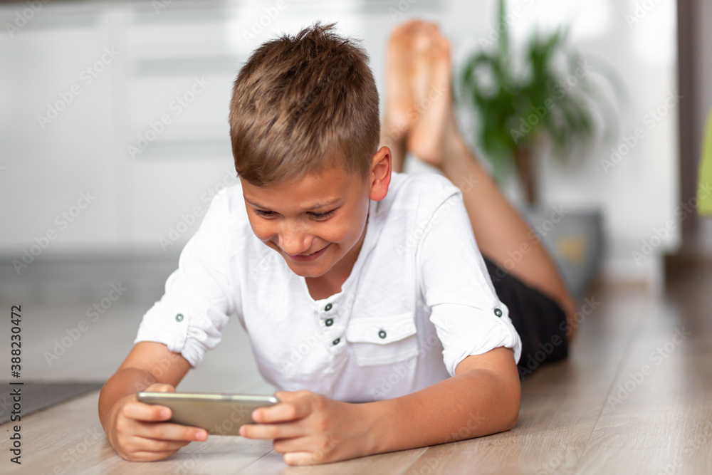 Happy boy using smart phone on the floor at home. Happy boy using smart phone on the floor at home.