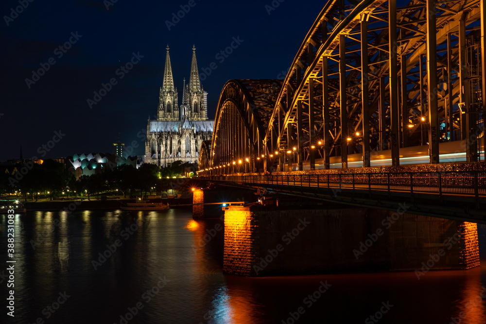Fototapeta premium Germany, Cologne, Cologne Cathedral, a large bridge lit up at night with Cologne Cathedral in the background