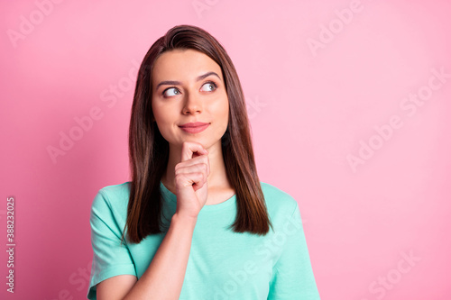 Photo portrait of thoughtful looking on space with finger wearing turquoise t-shirt isolated on pastel pink color background