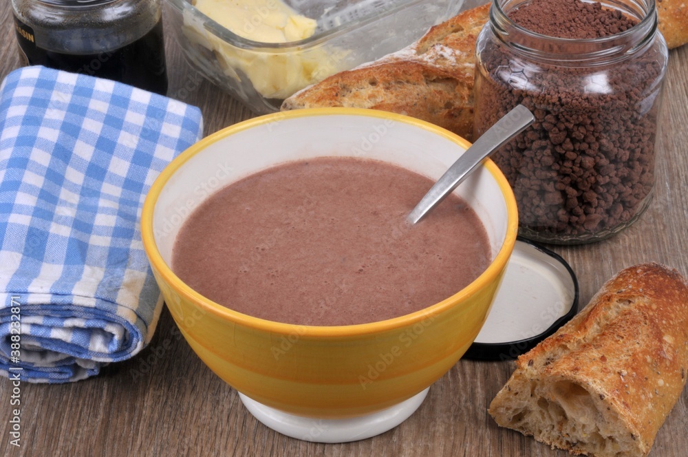 Bol de lait au chocolat avec un bocal de chocolat en poudre, du pain , un pot de miel et du beurre et une serviette de table en gros plan Bol de lait au chocolat avec un bocal de chocolat en poudre, du pain , un pot de miel et du beurre et une serviette de table en gros plan