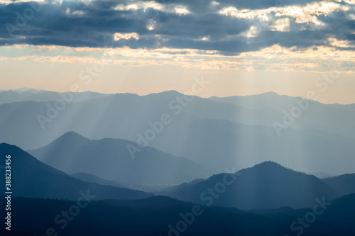 Sunlight shining through clouds to mountain range in Thailand.