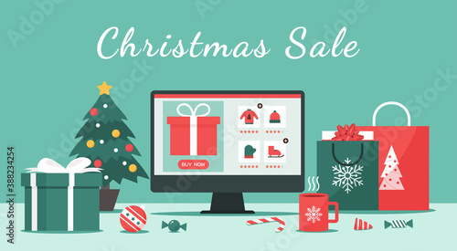 Christmas online shopping or winter holiday sale concept on a computer screen with gift boxes, shopping bags, candy on the desk, and text, vector flat illustration