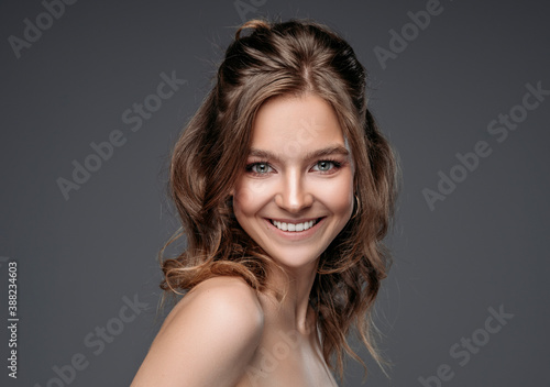 Portrait of a young smiling woman isolated on gray background