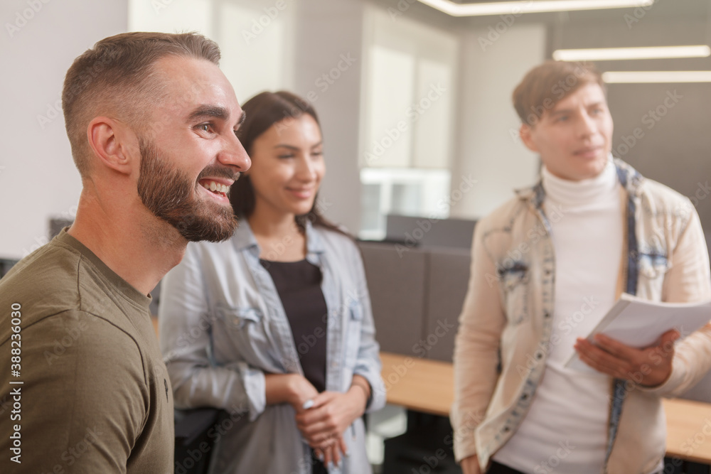 Obraz premium Handsome young businessman smiling, talking to his business team at the office