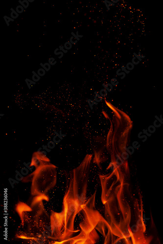 Fiery flame with sparks on a black background. Texture (element) for barbecue or cooking.