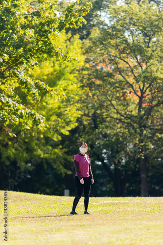 秋の朝の公園で散歩している主婦の様子