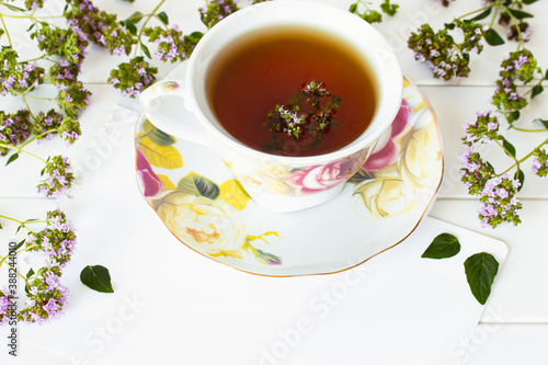 floral tea in a cup on a white background close-up. background with flowers oregano and a cup of tea with a shower.