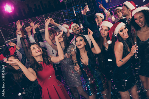 Photo of funny crazy people new year gathering enjoy raise palms hold glass x-mas headwear modern club indoors