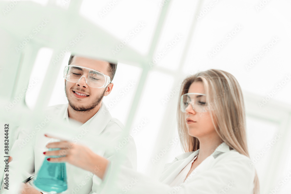 smiling scientist showing his colleague a flask of liquid. smiling scientist showing his colleague a flask of liquid.