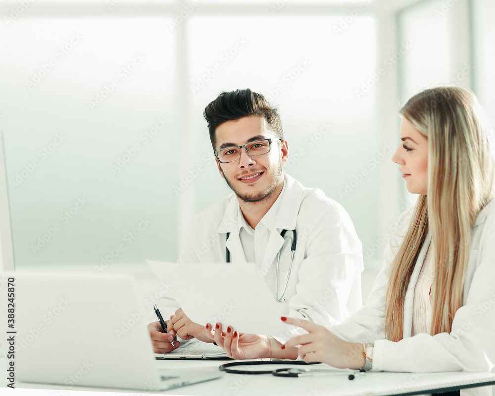 doctors colleagues talking sitting at a table in the office doctors colleagues talking sitting at a table in the office