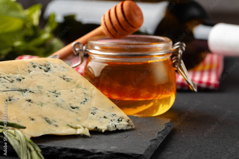 Cheese pieces and honey jar served on dark table Cheese pieces and honey jar served on dark table