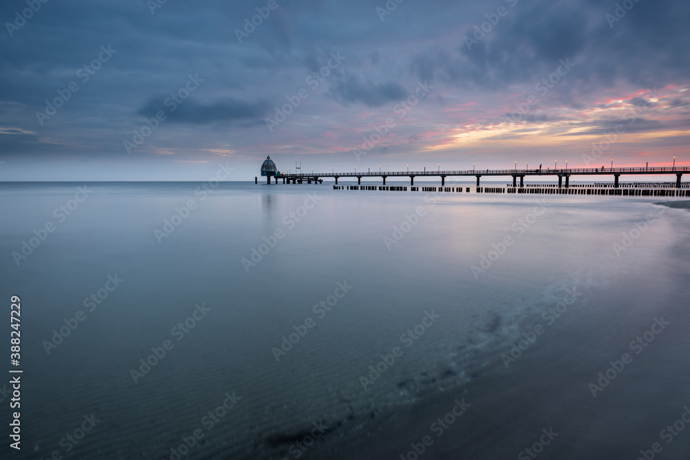 Cloudy sunrise at the beach at baltic sea with pier, Zingst, Western-Pomerania, Germany Cloudy sunrise at the beach at baltic sea with pier, Zingst, Western-Pomerania, Germany