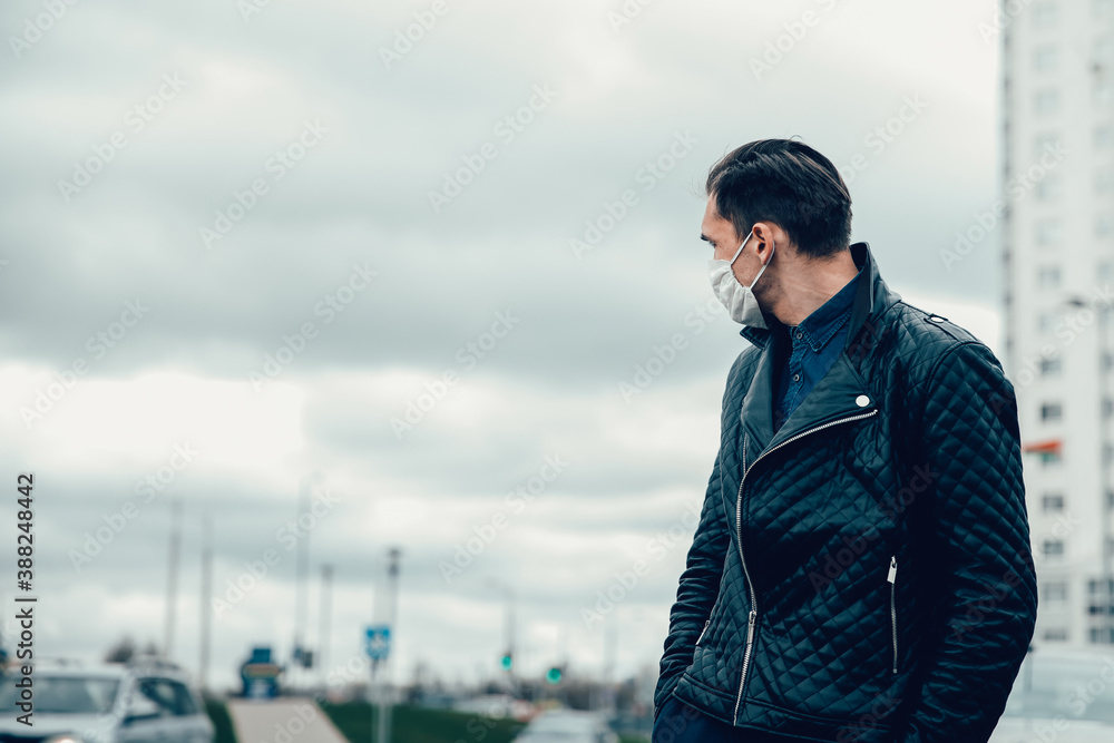 Obraz premium man in a protective mask looks at the empty street
