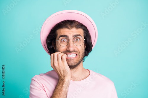 Portrait of staring man biting fingers wear pink cap glasses t-shirt isolated over teal color background