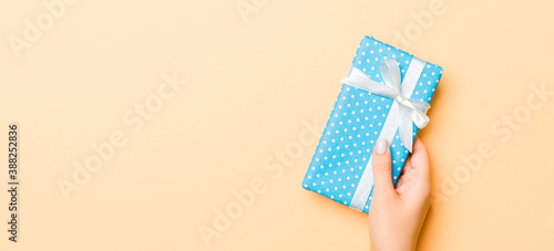 Flat lay of woman hands holding gift wrapped and decorated with bow on gold background with copy space. Christmas and holiday concept © sosiukin