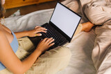 Young casual woman using laptop in her bed at home.