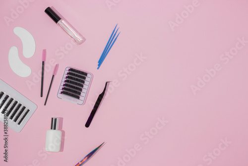 Fototapeta Naklejka Na Ścianę i Meble -  Things for the work of lash-makers, artificial eyelashes, microbrachis, glue, tweezers, combs, brushes. Eyelash extension, painting of eyebrows. Top view, pink background, free space for text.