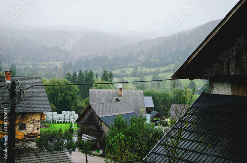 Scenic view of a heavy rain on a gray cold autumn day over the village against alps mountains.