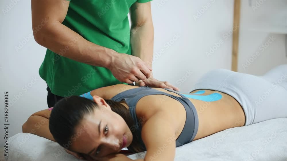 Woman lying down when doctor putting kinesio tape on her back. Woman lying down when doctor putting kinesio tape on her back.
