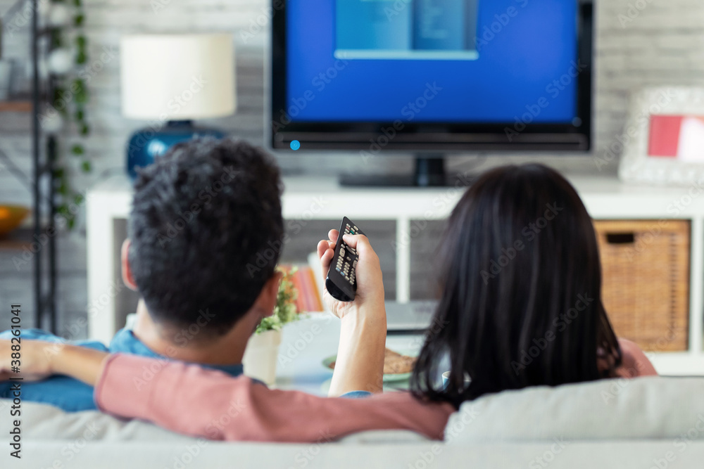 Relaxed young couple changing channels with the remote control while watching TV on the sofa at home. Relaxed young couple changing channels with the remote control while watching TV on the sofa at home.