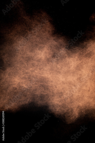Flying cocoa powder on isolated black background, brown chocolate dust cloud. Creative sweet hurricane storm tornado concept, copy text space. Dark sand abstract screensaver, explosion burst texture