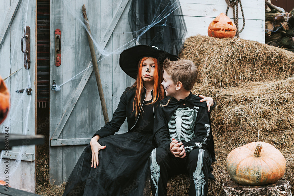 children a boy in a skeleton costume and a girl in a witch costume having fun at a Halloween party on the decorated porch