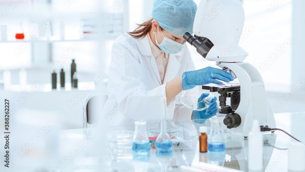 close up. female scientist looking through a microscope.
