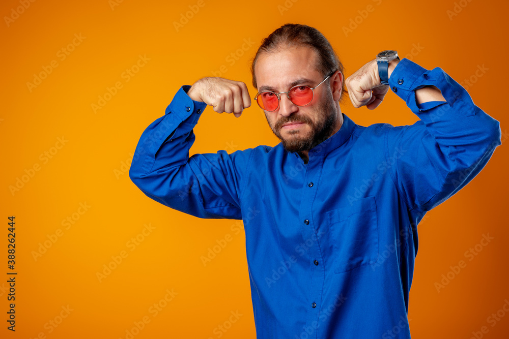 Naklejka premium Bearded man in shirt showing bicep and looking at camera