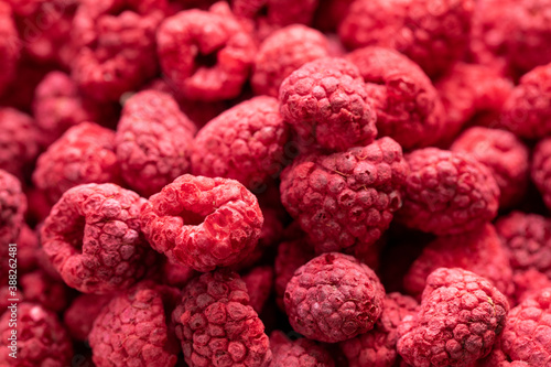 Fototapeta Naklejka Na Ścianę i Meble -  Macro shot of freeze dried organic raspberries, raw delicious snack, cooking baking ingredients. Red berries juicy summer background. Natural sugars, healthy food, fresh fruits concept, text space