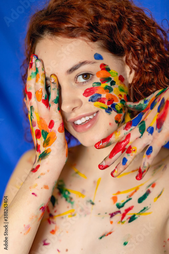 Close-up portrait of red curly haired woman Young Close-up portrait of red curly haired woman Young cheerful soiled in paint. Portrait of a girl with a creative pattern on her face. Concept photograph