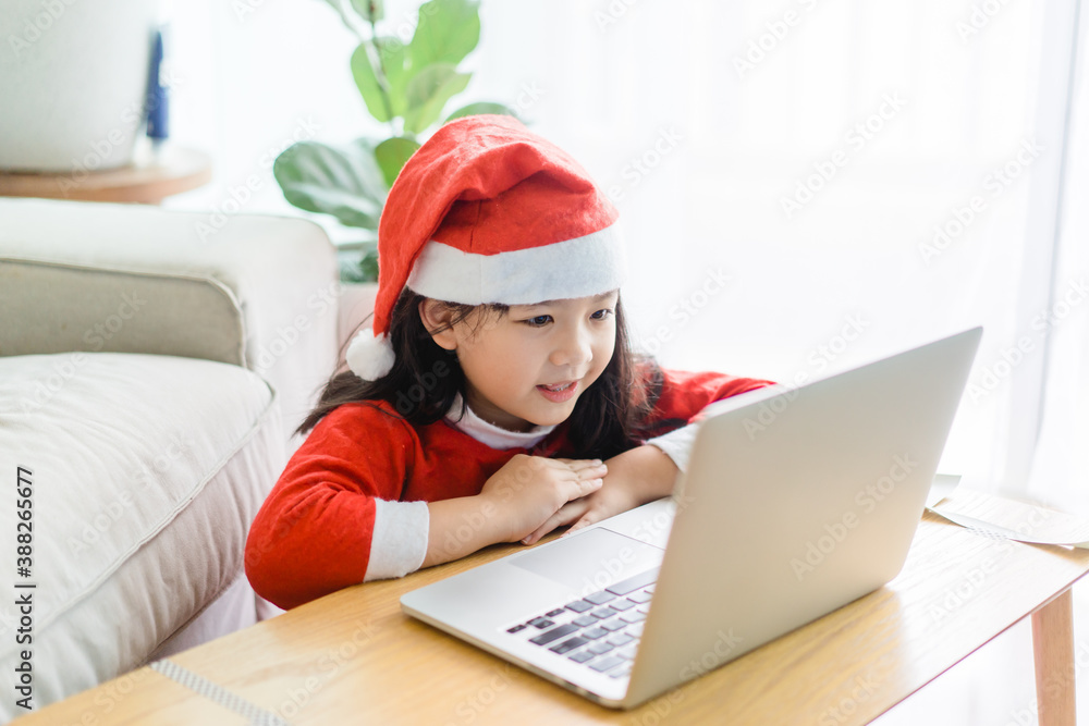 Asian girl with santa hat on christmas holidays party.Happy girl talking video cameara on laptop.Technology online with laptop at home.New normal.Covid-19 coronavirus.Social distancing.stay home. Asian girl with santa hat on christmas holidays party.Happy girl talking video cameara on laptop.Technology online with laptop at home.New normal.Covid-19 coronavirus.Social distancing.stay home.