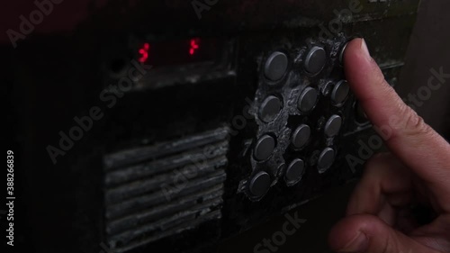 human finger presses the intercom button, a man opens the door by entering the code on the old intercom