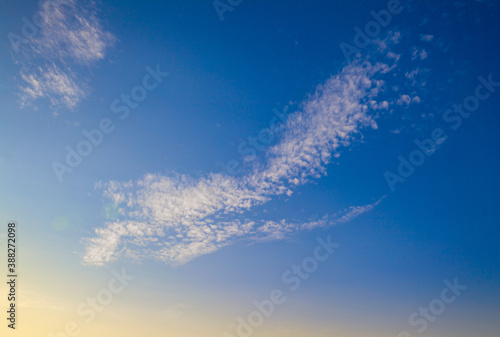 Cloud on a background of blue sky and yellow dawn with highlights from the sun