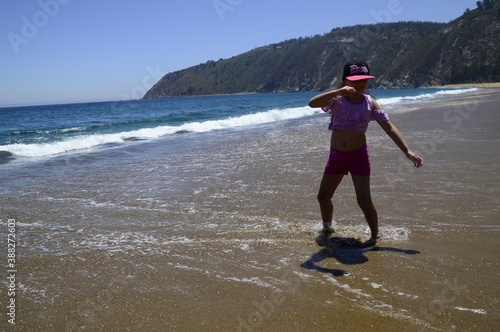 Niña joven bailando y jugando sola en el agua en la playa photo