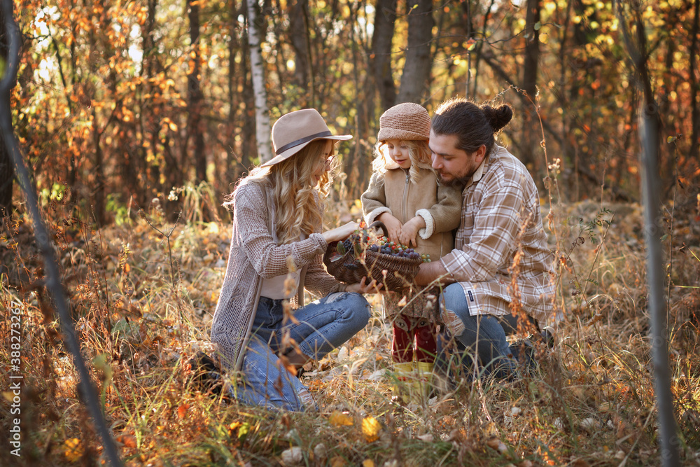 happy family with a basket of berries in the woods in autumn