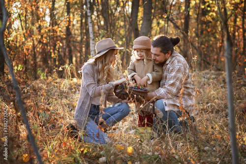 happy family with a basket of berries in the woods in autumn