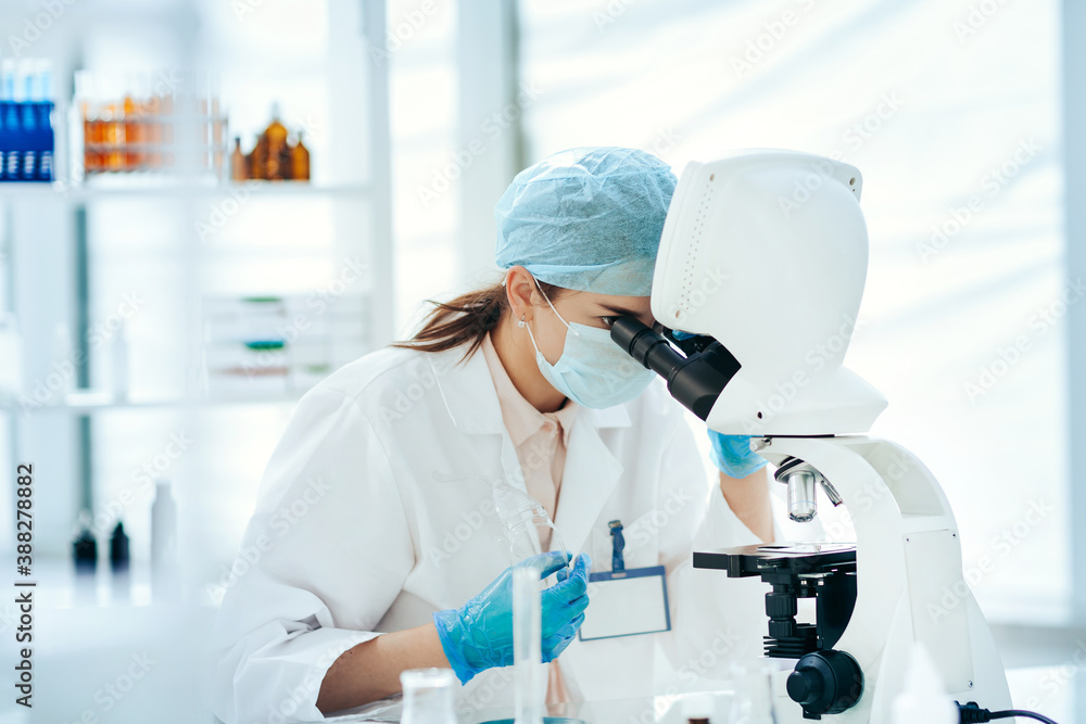 close up. female scientist looking through a microscope.