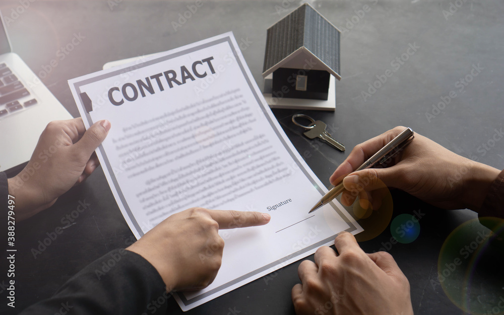 Agreeing to buy a house, a man's hand is about to sign an agreement or a contract for buying a home that he has spoken to with the real estate agent. Agreeing to buy a house, a man's hand is about to sign an agreement or a contract for buying a home that he has spoken to with the real estate agent.