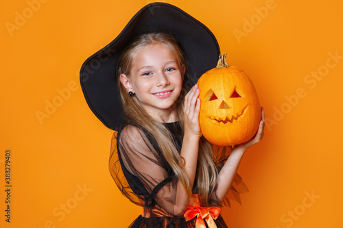 Fotobehang Happy child girl in witch costume holding pumpkin
