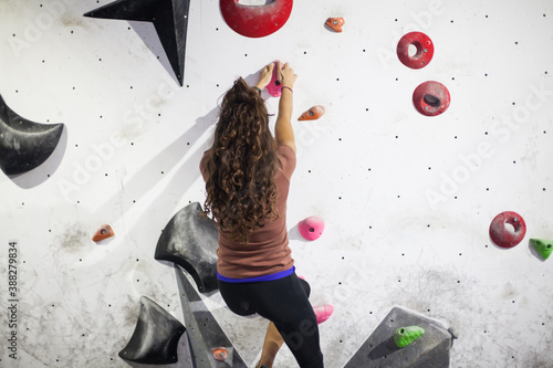 Obraz na plátně young fit woman climber moving up on rock wall, climbing on artificial wall indoors