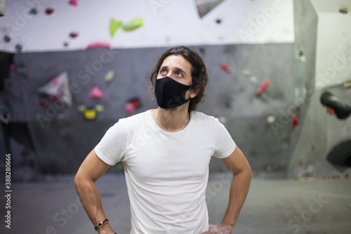 young fit male climber wearing mask on steep rock indoors