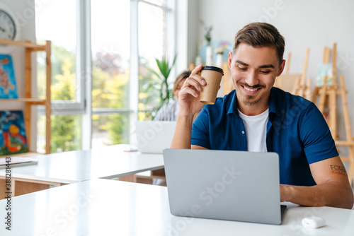 Young caucasian man and woman studying with laptops in classroom