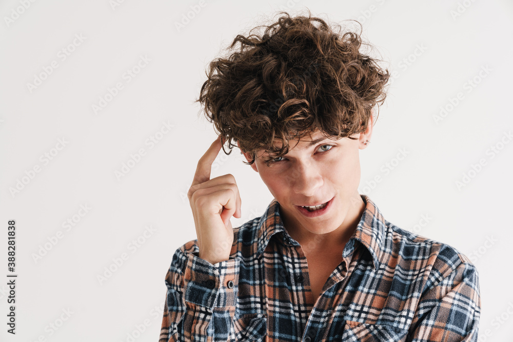 Cheerful curly guy smiling and pointing finger at his head Cheerful curly guy smiling and pointing finger at his head