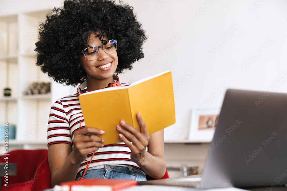 Smiling african american student girl doing homework with laptop Smiling african american student girl doing homework with laptop