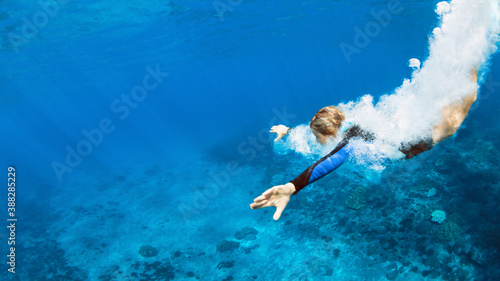 Happy family - active teenage girl jump and dive underwater in tropical coral reef pool. Travel lifestyle, water sport, snorkeling adventure. Swimming lessons on summer sea beach vacation with kids
